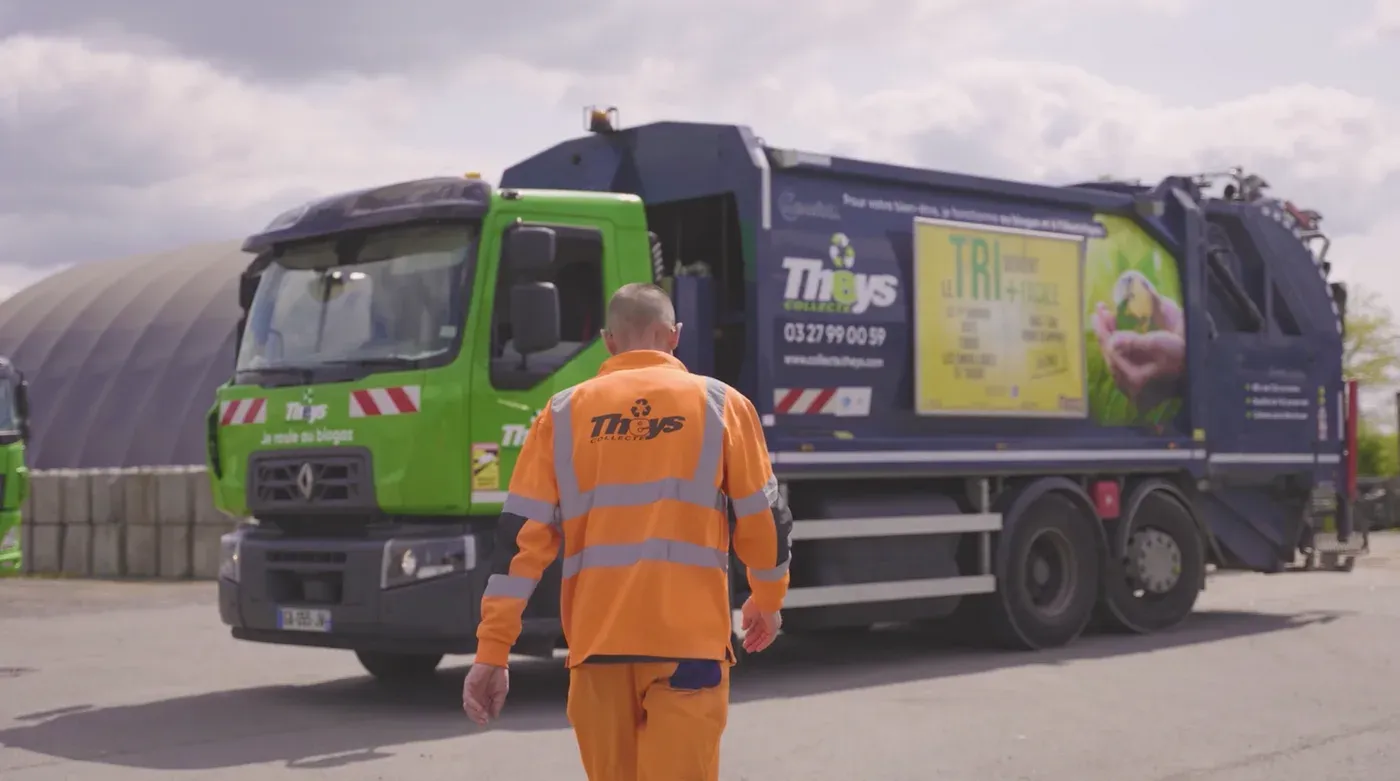 Agent THEYS en tenue haute visibilité devant un camion de collecte